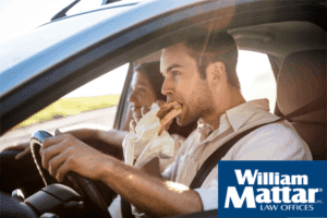 man eating a burger while driving